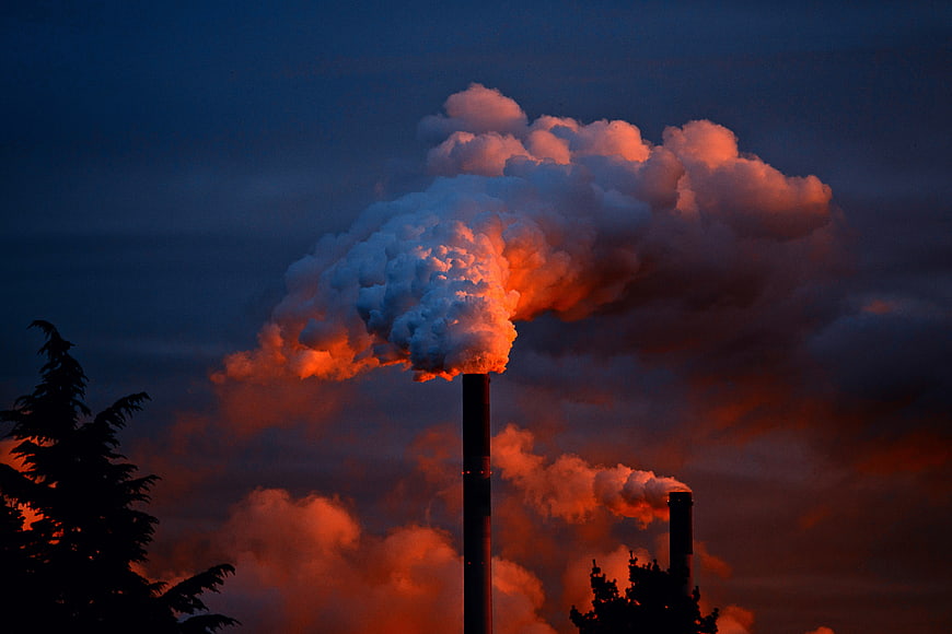 Industrial Factory Smokestacks Emitting Smoke Against Dramatic Sunset Sky