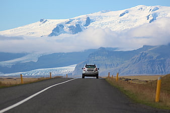 SUV driving on road towards snowy glacier mountain