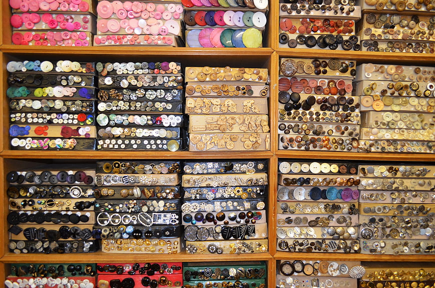 Organized wooden shelves filled with colorful vintage and modern sewing buttons