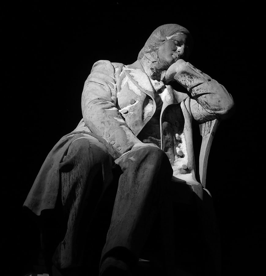 Black and white statue of a seated classical musician