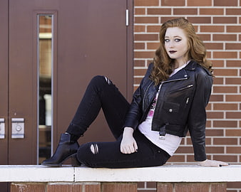 Redhead woman in leather jacket sitting on bench
