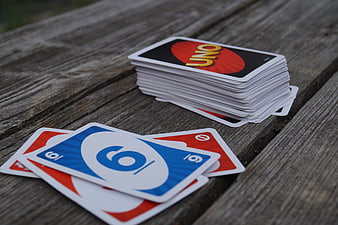 Stack of Uno Cards and Scattered Playing Cards on Weathered Wooden Table