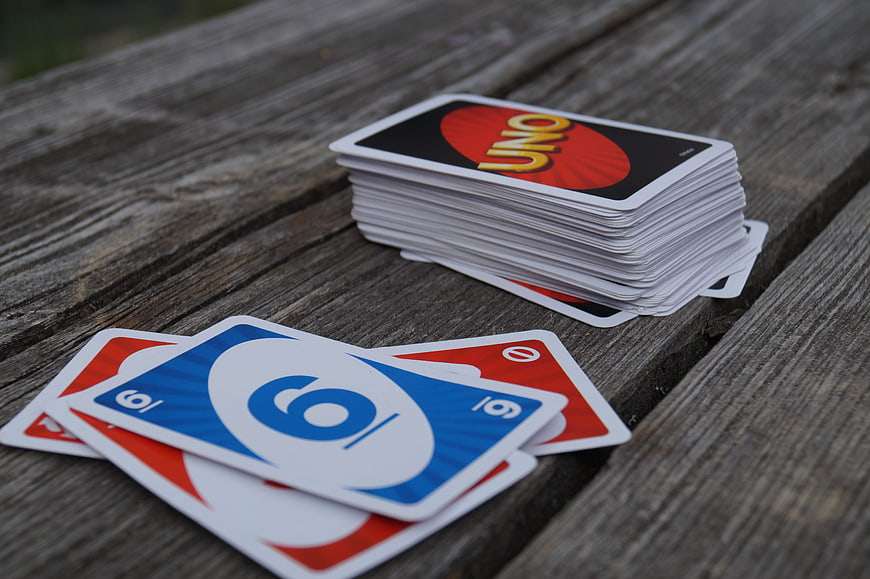 Stack of Uno Cards and Scattered Playing Cards on Weathered Wooden Table