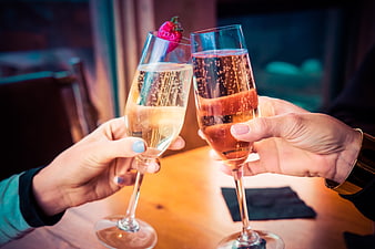 Two hands clinking champagne glasses in a celebratory toast