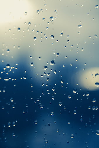 Raindrops on Glass Window with Blurred Blue Background