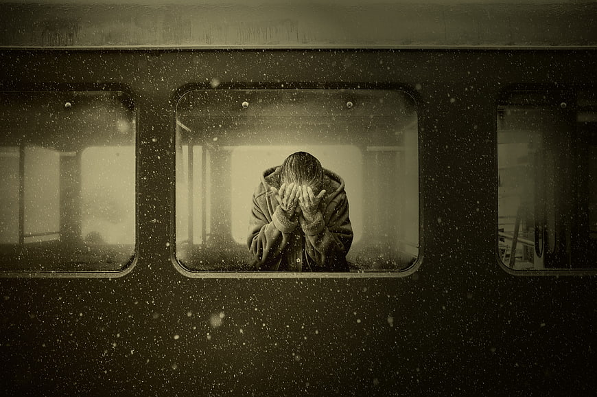 Lonely woman crying in train window during snowfall