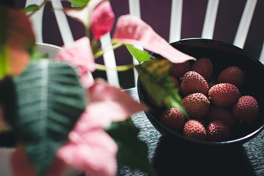 Fresh lychee fruit in black bowl with pink flowers