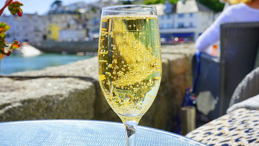 Glass of sparkling wine on outdoor table with harbor view