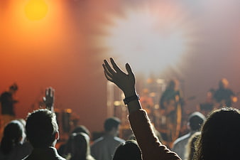 Silhouette of hand raised at live concert with stage lights