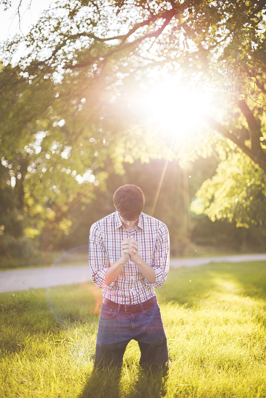Man Kneeling in Prayer in Sunlit Park