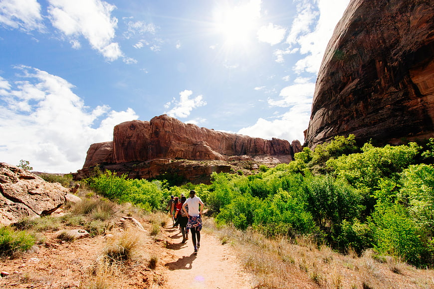 Hikers walking on trail through red rock canyon landscape