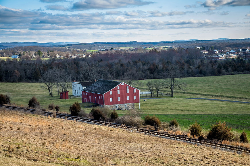 Red Barn and White House in Rural Landscape with Train Tracks