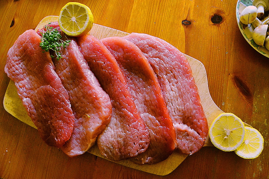Raw Pork Chops on Wooden Board with Lemon and Herbs