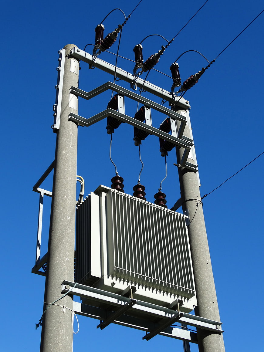 Low angle view of electrical transformer on utility pole against blue sky