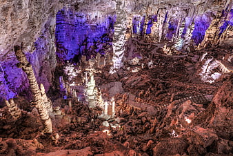 Illuminated limestone cave formations with purple and warm lighting