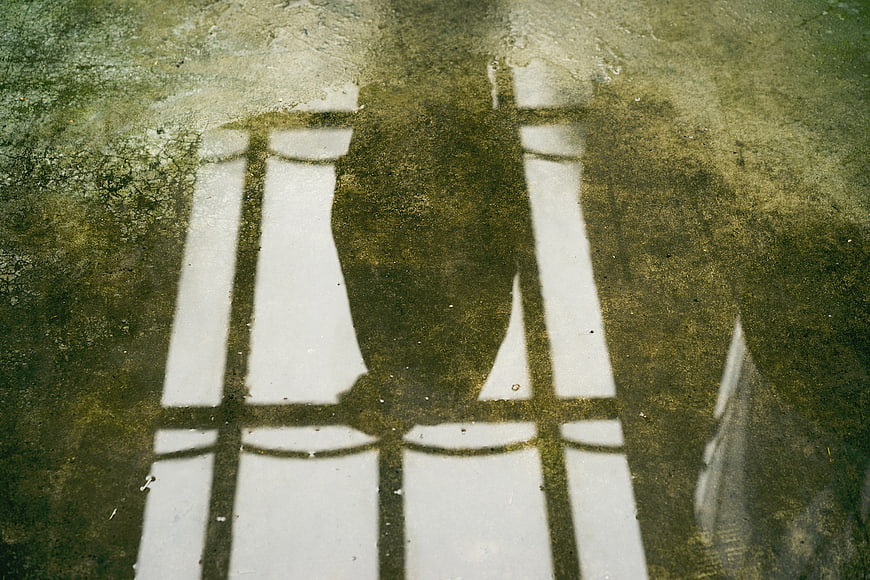 Shadow of person sitting on chair on wet stone floor
