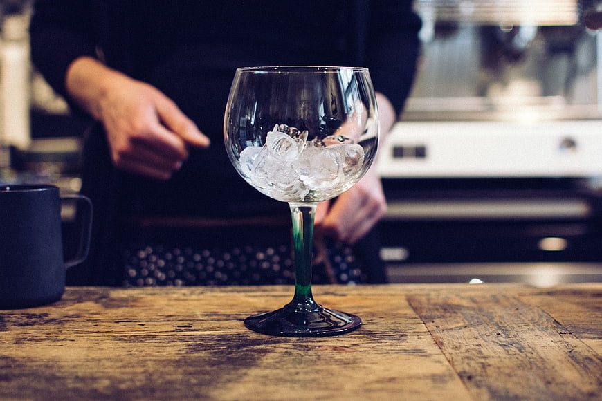Glass with ice cubes on wooden bar counter