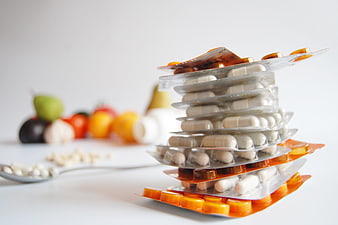 Stack of medicine blister packs with blurred fruit background