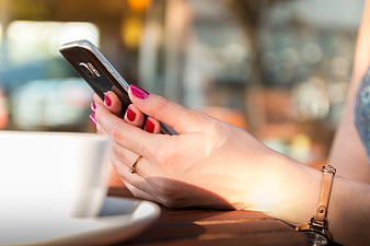 Woman's Hands Using Smartphone at Cafe Table