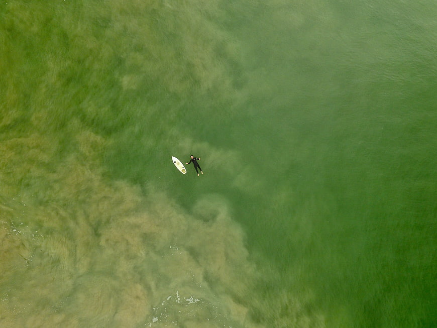 Aerial view of surfer in green ocean water