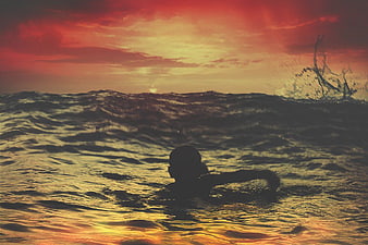 Silhouette of Boy Swimming in Ocean at Sunset