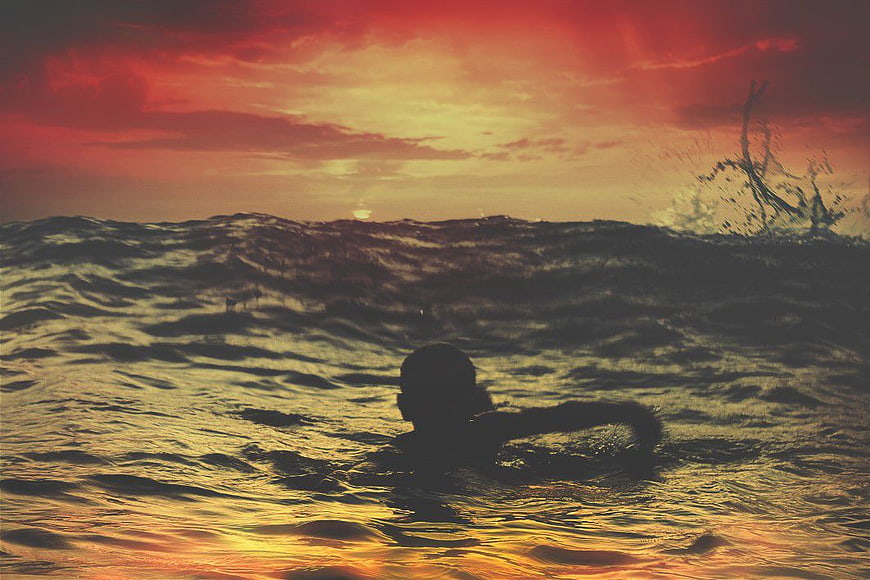 Silhouette of Boy Swimming in Ocean at Sunset