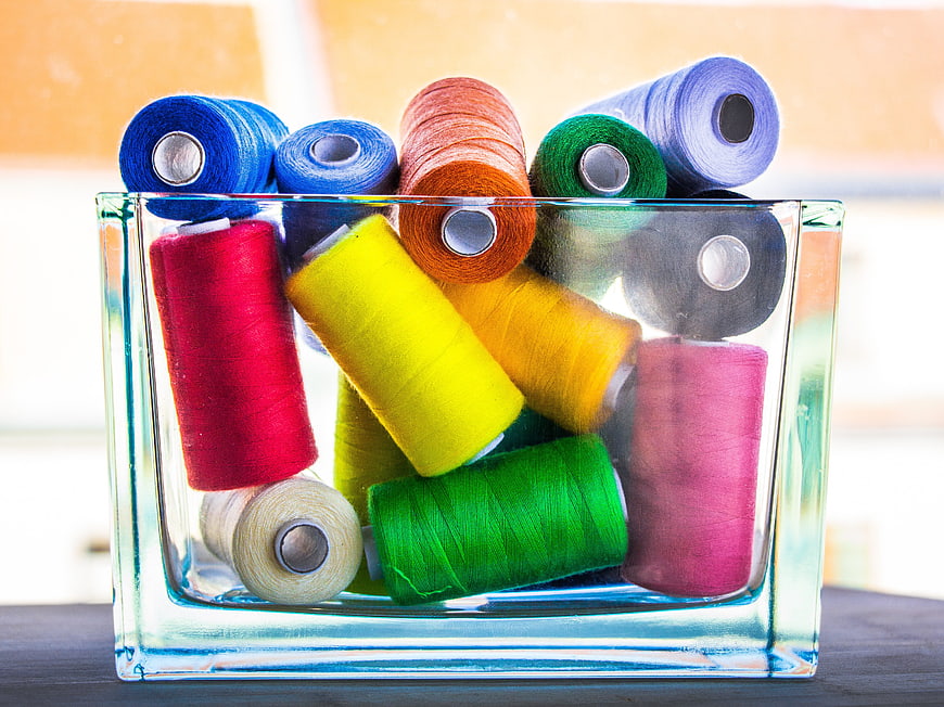 Colorful Sewing Thread Spools in Glass Container