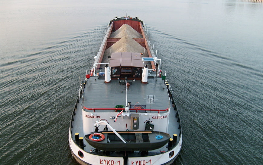 Aerial view of cargo barge transporting sand on river