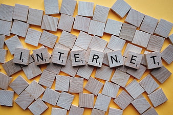 Scattered Scrabble Tiles Spelling Internet on Yellow Background