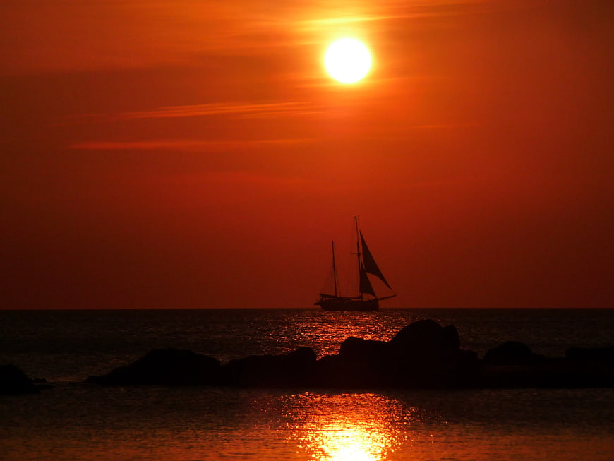 Silhouette of Sailboat on Ocean at Vibrant Sunset