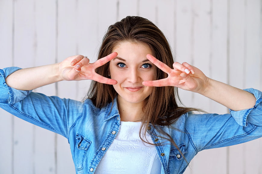 Young woman making peace signs near eyes