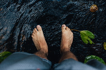 Bare feet in a dark flowing river stream