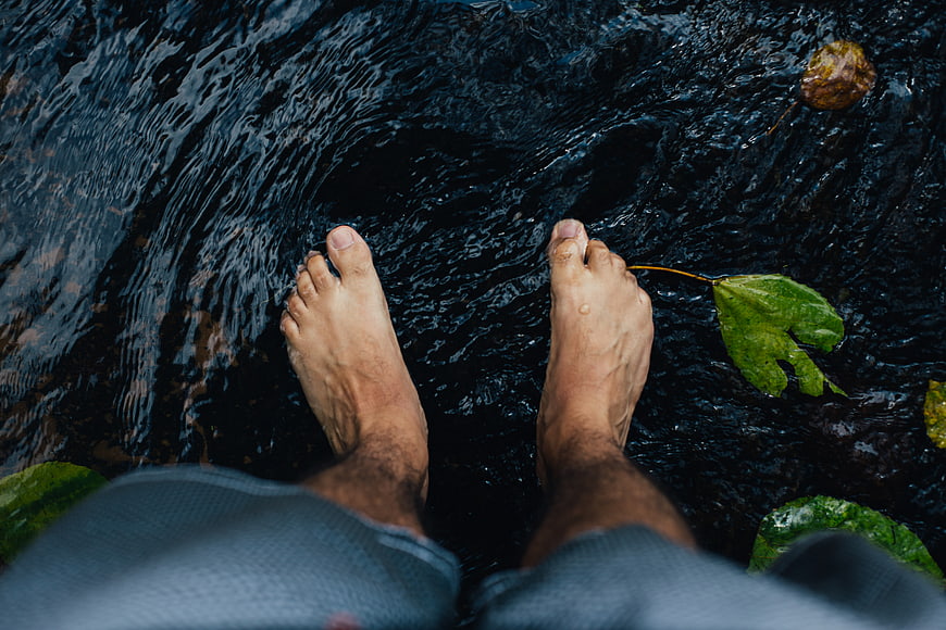 Bare feet in a dark flowing river stream