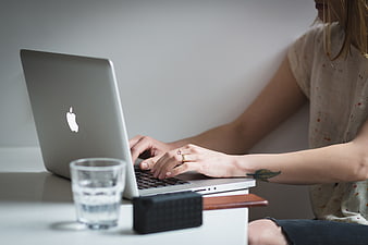 Woman Typing on Laptop at Desk with Water Glass
