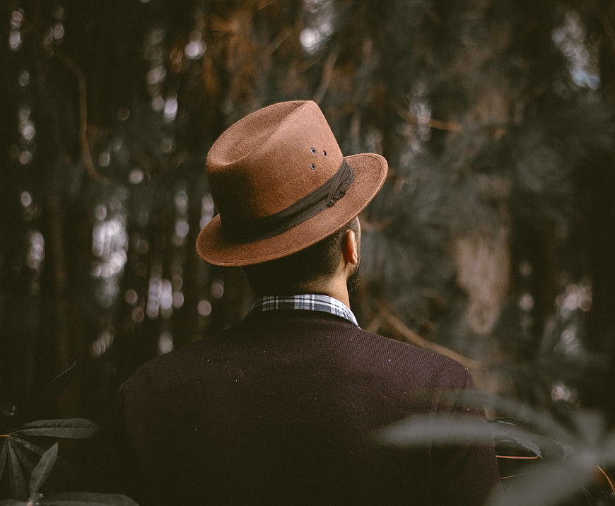 Man in Fedora Hat Standing in Dark Forest