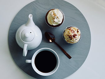 Top view of cupcakes, coffee, and teapot on a blue tray