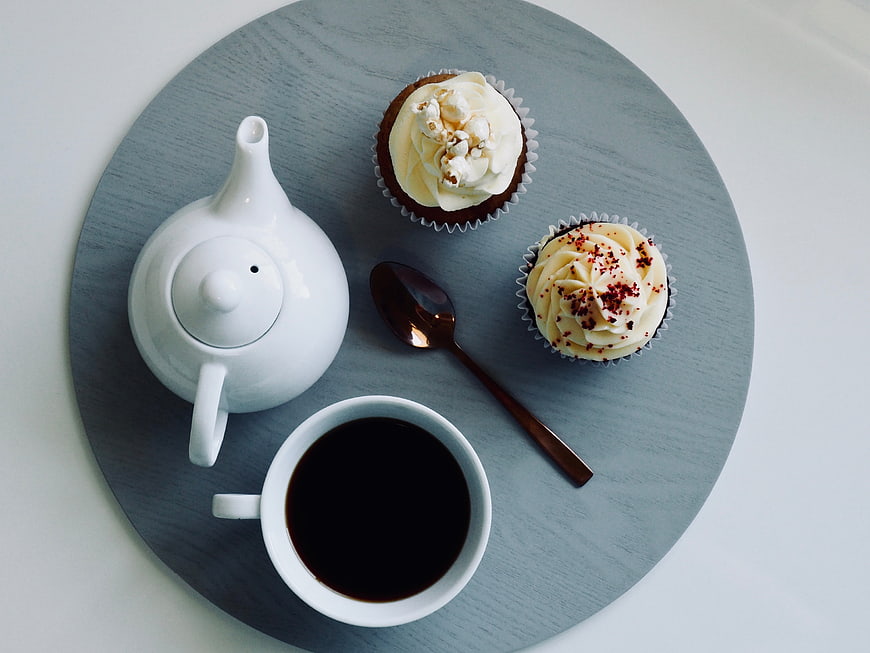 Top view of cupcakes, coffee, and teapot on a blue tray