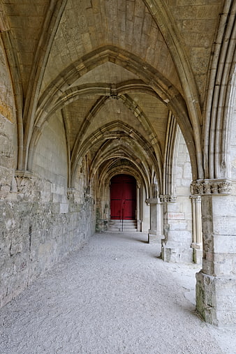 Gothic stone cloister with vaulted arches and red door