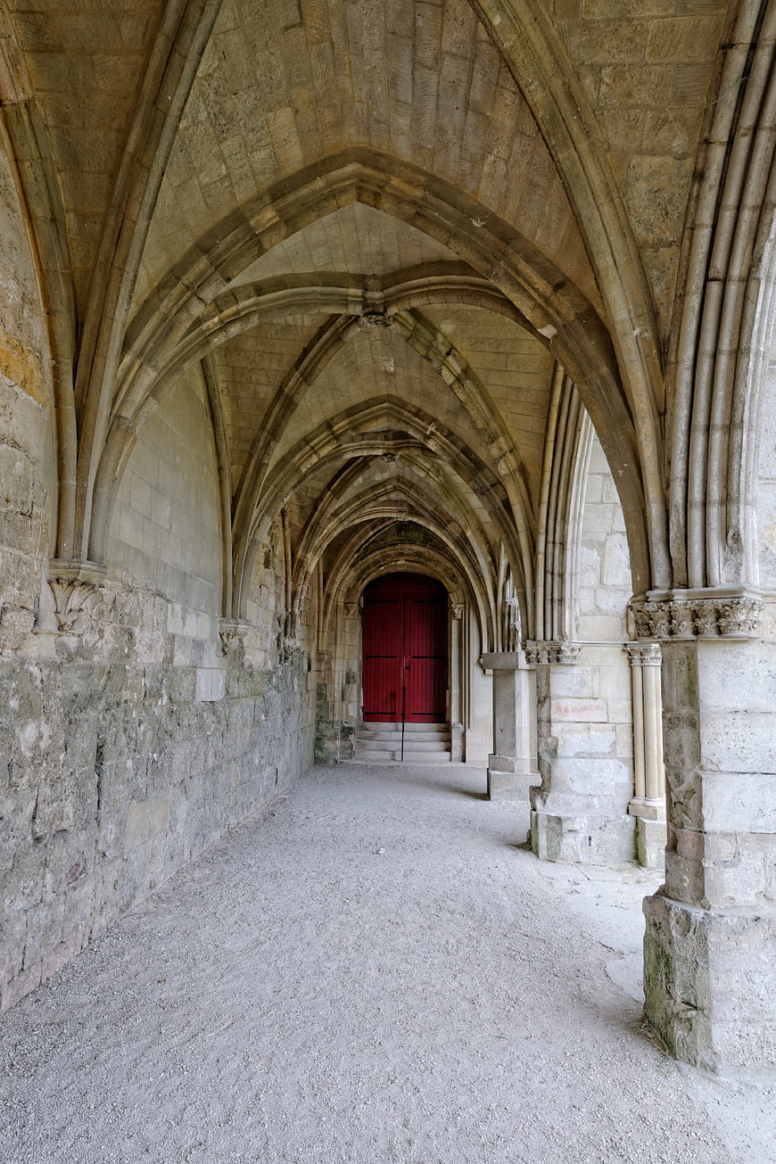 Gothic stone cloister with vaulted arches and red door