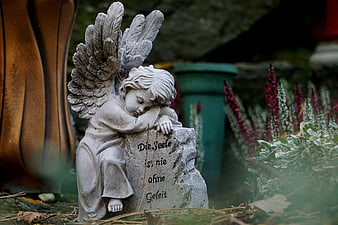 Grieving Angel Statue On Stone Tombstone In Garden