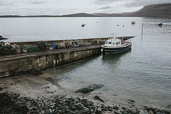 Fishing boat docked at concrete pier in coastal harbor