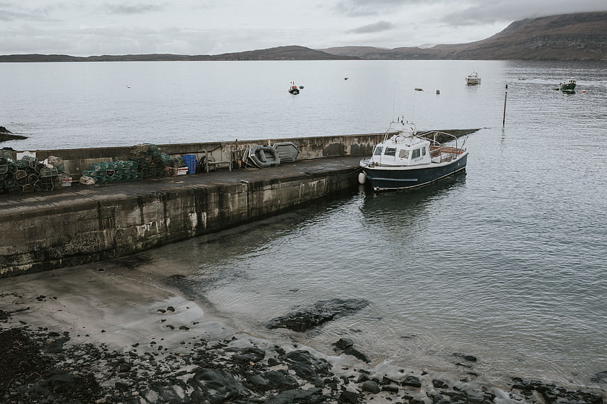 Fishing boat docked at concrete pier in coastal harbor