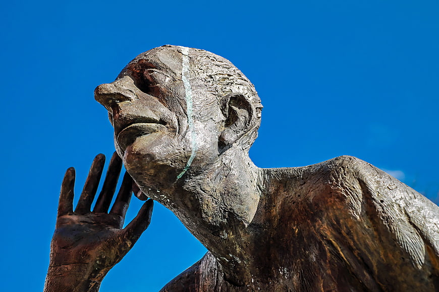 Bronze Sculpture of Man Listening Against Blue Sky
