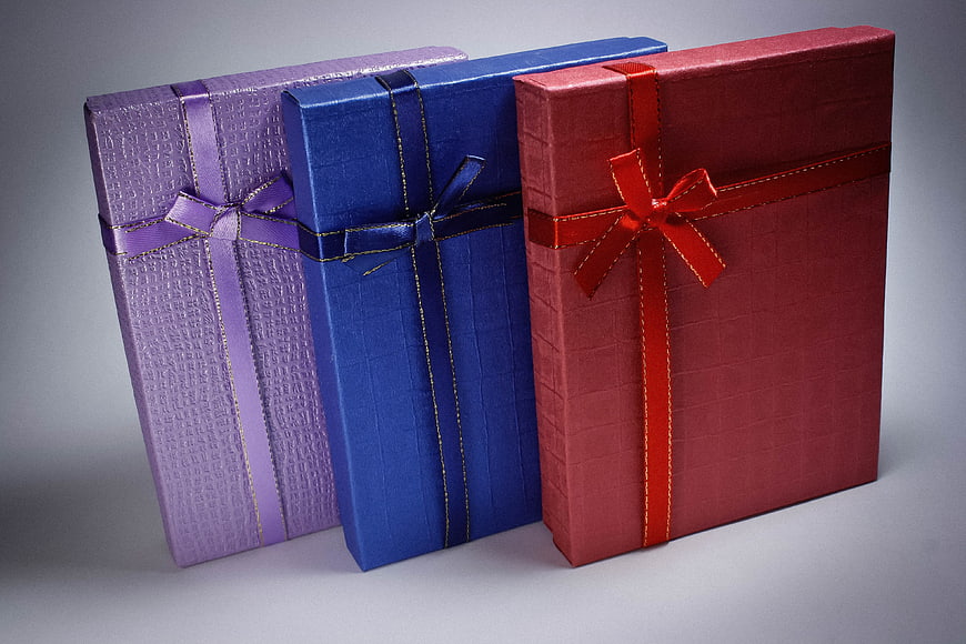Three Colorful Gift Boxes with Ribbons on Gray Background