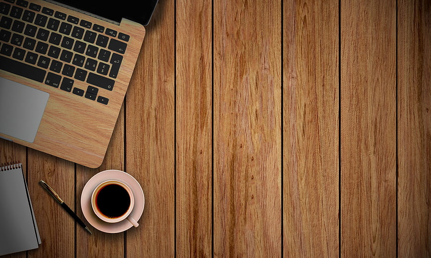 Flat lay workspace with laptop, coffee, and notebook on wood