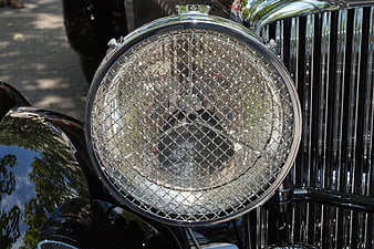 Close-up of vintage car headlight with chrome grille