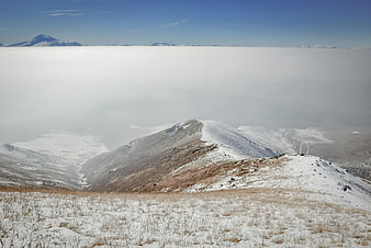 Snowy mountain ridge above sea of clouds winter landscape