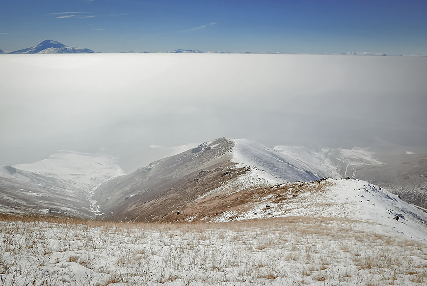 Snowy mountain ridge above sea of clouds winter landscape