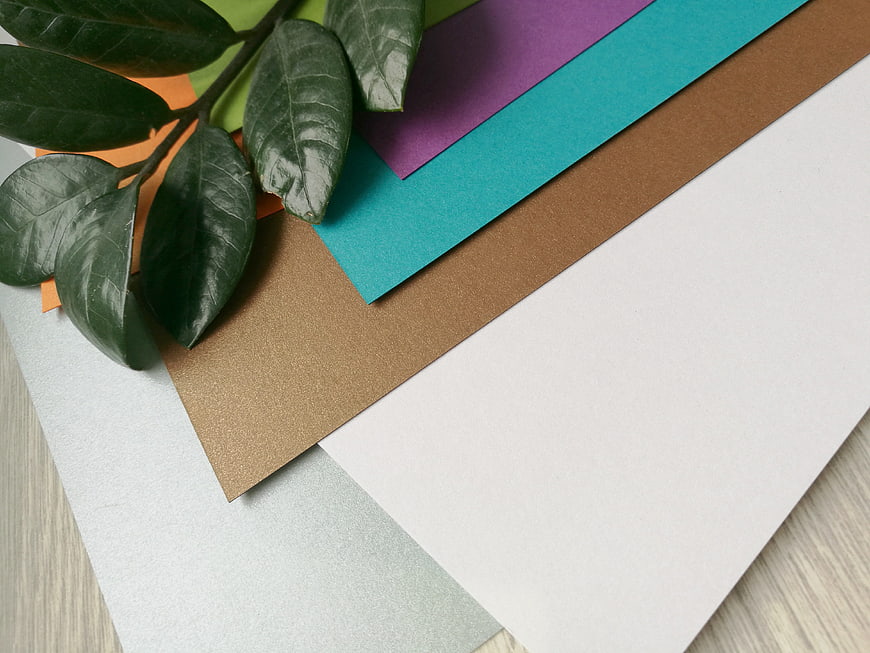 Stack of colorful designer paper sheets with green leaves