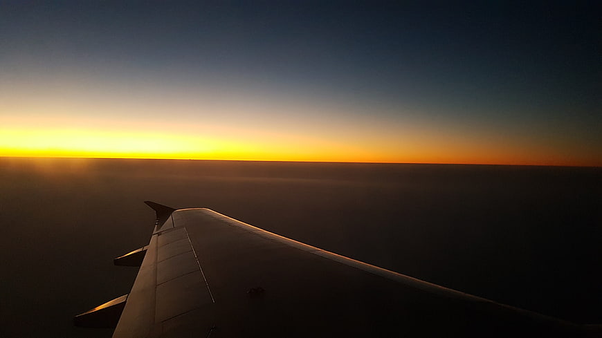 Airplane Wing at Sunset Over Ocean Horizon